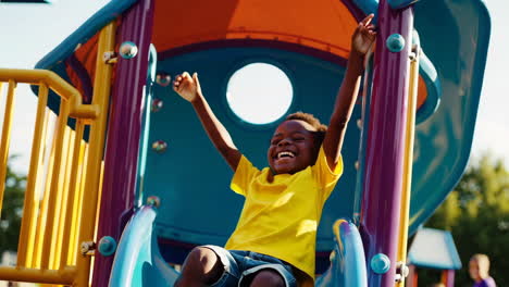 joyful young boy playing on a colorful playground slide