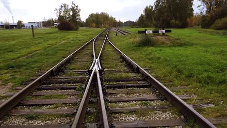 POV-Des-Fluges-über-Eisenbahnschienen-Mit-Gras,-Felsen-An-Einem-Hellen-Herbsttag