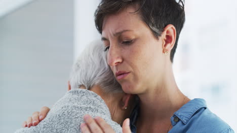 una mujer joven consolando a su madre mayor molesta