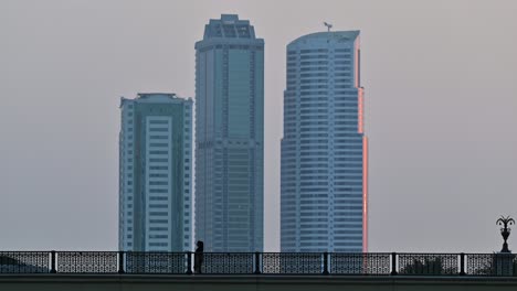 4k: una dama caminando por el puente, tráfico de la ciudad y torres residenciales modernas en el fondo