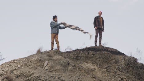 Far-View-Of-Two-Teenage-Boys-In-Winter-Clothes-On-Top-Of-A-Mountain-On-A-Windy-Day