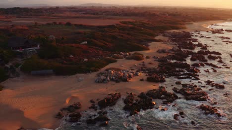 sun rises as waves from the pacific ocean crash in front of beautiful luxury rental villas in oaxaca mexico