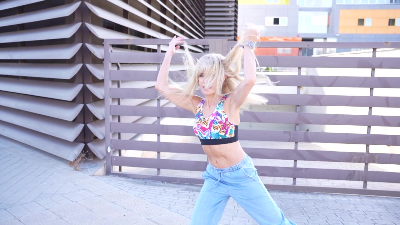 A joyful young woman dancing outdoors in an urban setting with colorful expressions of happiness