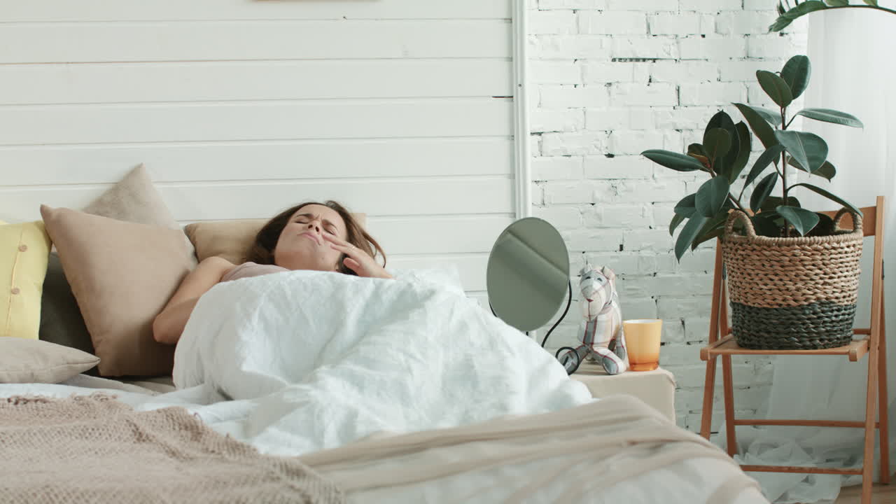 임신 중인 여성이 침대에서 메스꺼움을 느끼고 임신 중인 여성이 아침에 집에서 병을  ⁇ 고 있습니다.