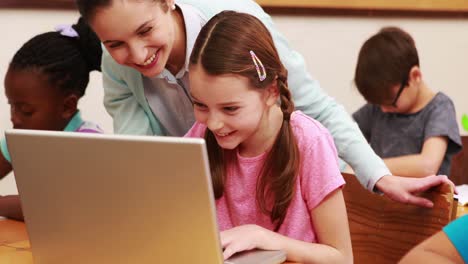 Teacher-helping-pupil-with-laptop