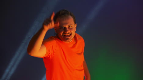 crazy man dancing in the neon light of the ridiculous dance. funny man on a colored blue background