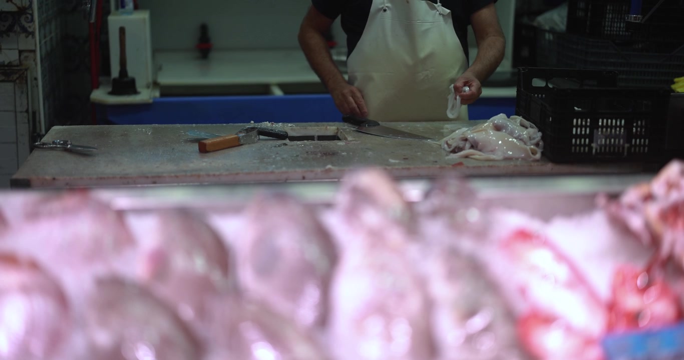 Fishmonger Cleaning and Preparing Fresh Squid at a Market Stall