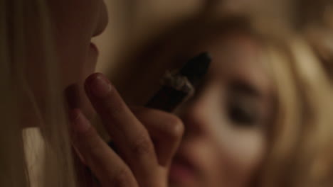 woman looking at a mirror, smoking a cigar