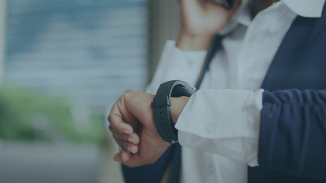 Businesswoman raising left wrist and shifting smartwatch causing data overlays while taking call