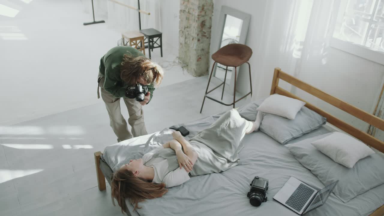 Photographer Capturing Images of Beautiful Woman Posing on Bed in Studio