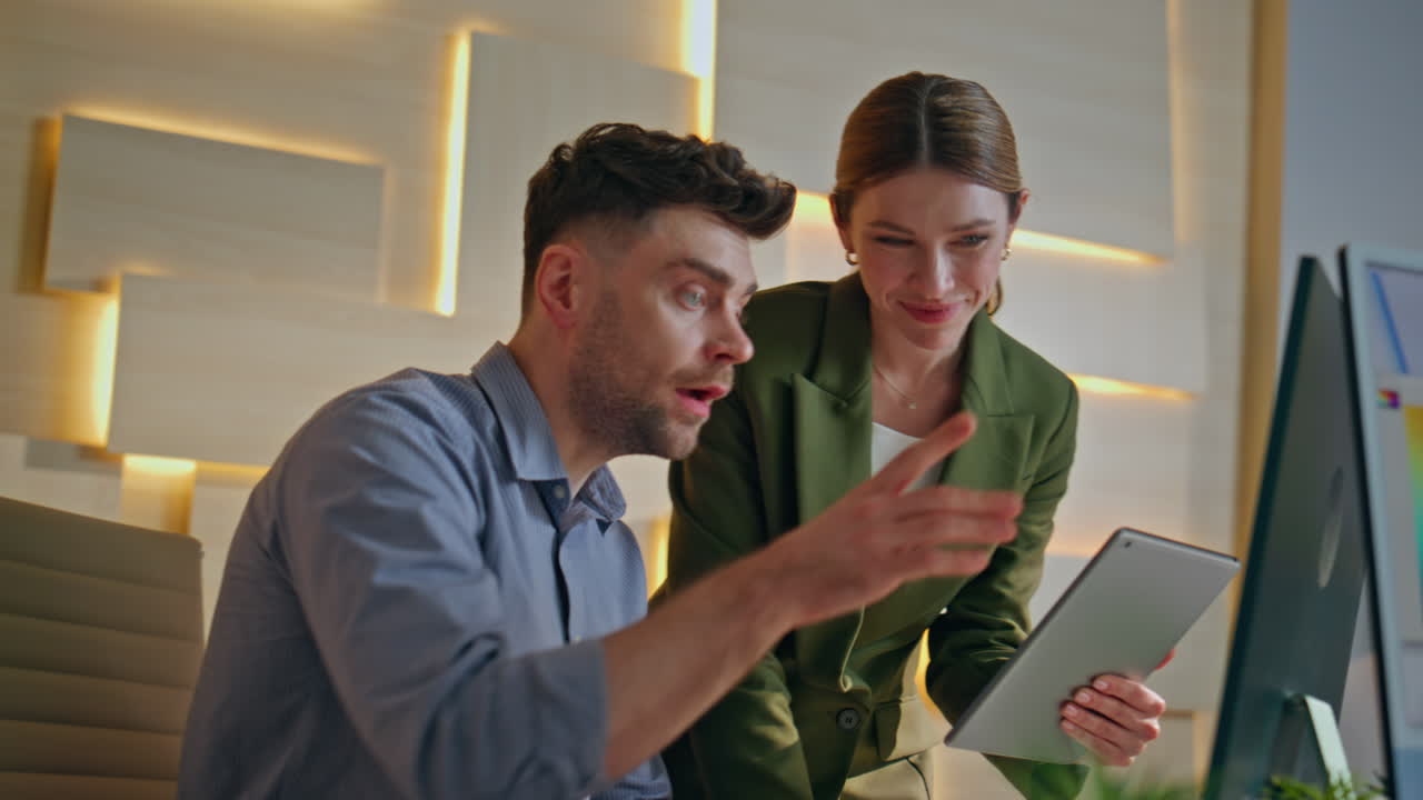 Two colleagues rejoicing project success working together at agency close up.