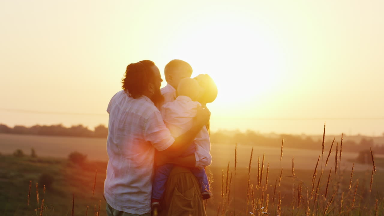행복한 어린 시절 부모는 석양의 광선에 자녀를 안아