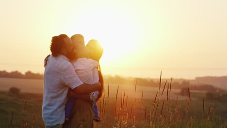 Los-Padres-De-La-Infancia-Feliz-Abrazan-A-Sus-Hijos-En-Los-Rayos-Del-Sol-Poniente