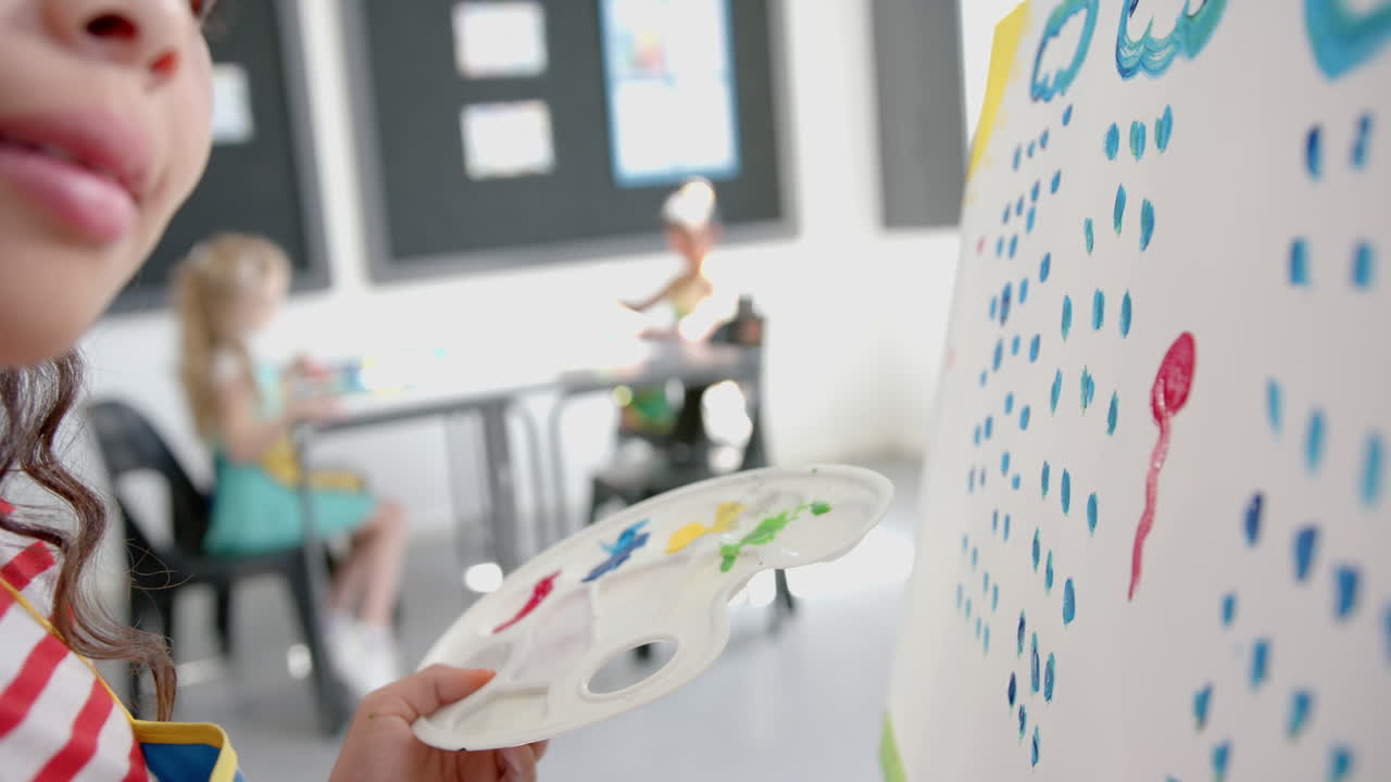 In school, child painting on canvas with palette in art classroom