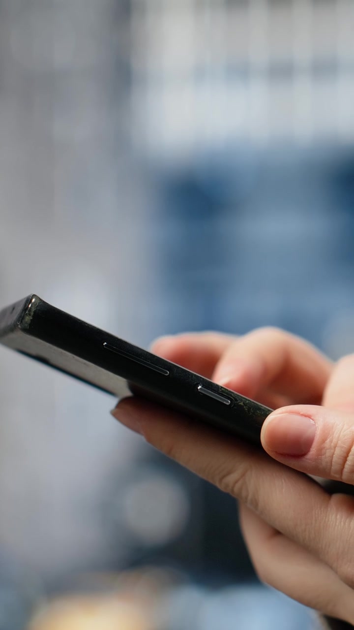 Video verticale: Primo piano delle mani di una donna d'affari che toccano lo schermo dello smartphone su un viale cittadino.