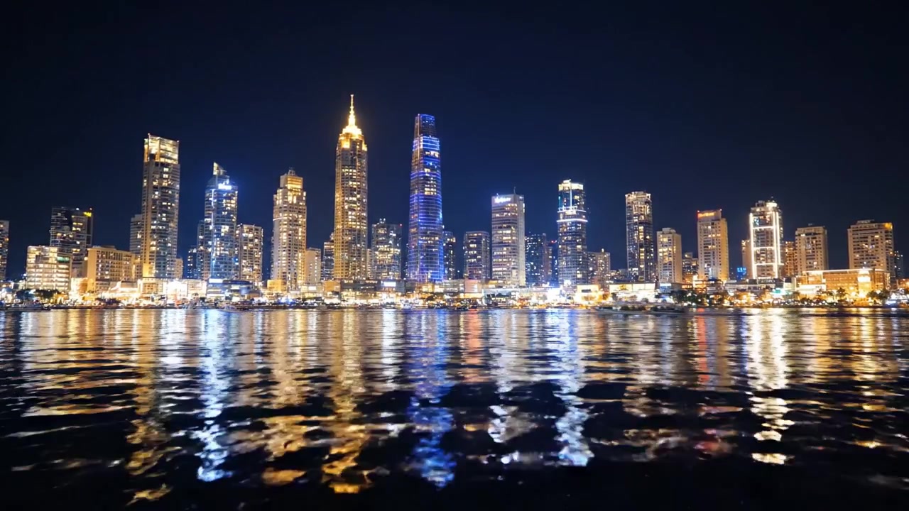 Stunning Cityscape at Night: A Captivating View of Skyscrapers Reflected in Serene Waters with Dazzling Lights Illuminating the Urban Landscape