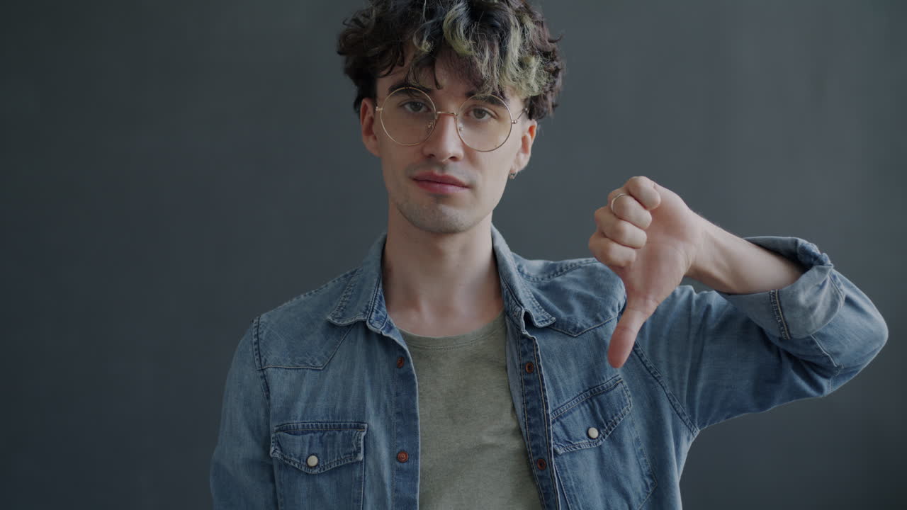 Man with Glasses and Denim Jacket Giving Thumbs Down