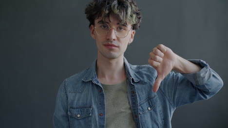 man with glasses and denim jacket giving thumbs down