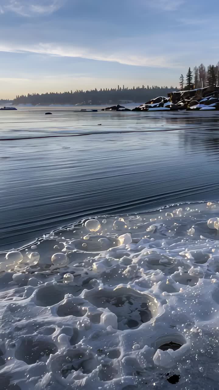 Vertical video: Panning camera over ice floes and lake after sun glint, showing forest reflection