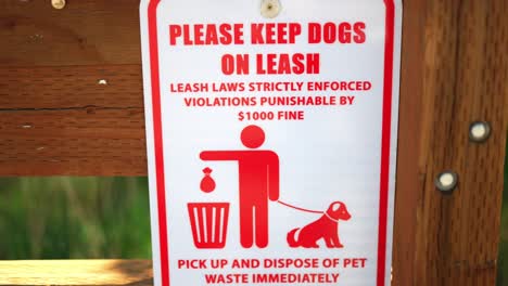 please keep dog on leash, laws strictly enforced, violations punishable by $1000 fine, and pick up your pet waste poop sign, posted at public national park hiking trail