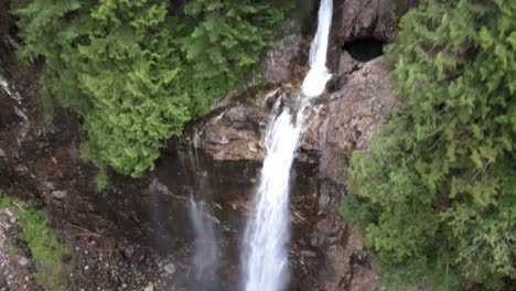 Rising-up-quickly-revealing-dense-forest-surrounding-Franklin-Falls,-aerial