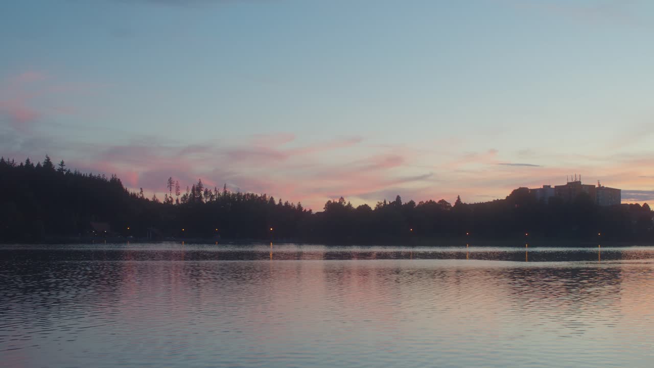 Wide shot showing blue hour after sunset at horizon. Tree reflection in water surface. Beautiful nature shot.