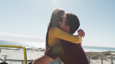 happy caucasian couple hugging near beach buggy by the sea