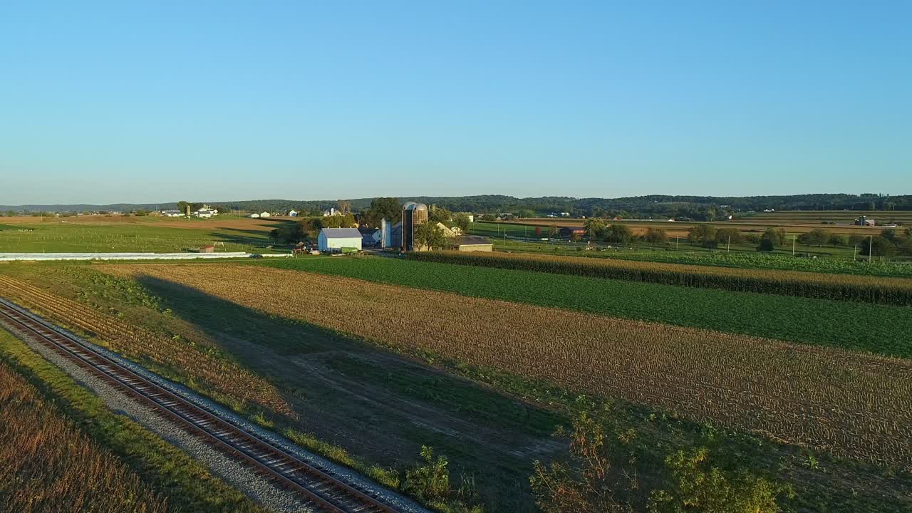 una vista de drones de las tierras de cultivo y los cultivos que esperan ser cosechados durante la hora dorada en un soleado día de otoño sin nubes
