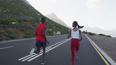 diverse fit couple exercising running on a country road near mountains