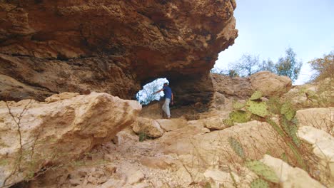 man enjoy walking into the natural bridge in curacao on sunny day - steady shot