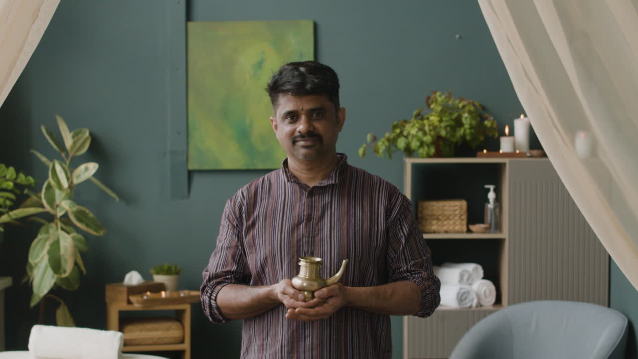 Uomo con vaso di olio ayurvedico in una spa