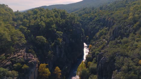 aerial view of a mountain canyon with a river and lush forest