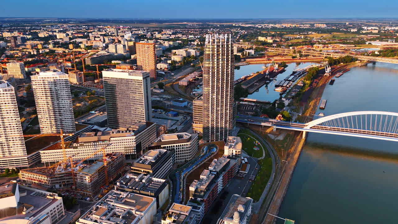 Modern neighborhood with a construction cite at the waterfront of the Danube. Vast cityscape of Bratislava, Slovakia at sunset