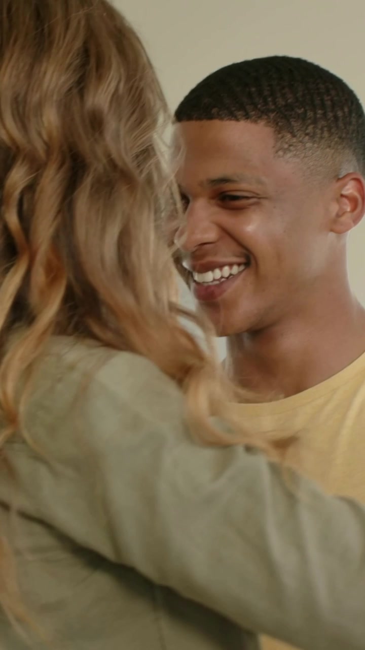 Vertical video: Holding hands couple in olive and yellow clothing embracing in kitchen, smartwatch