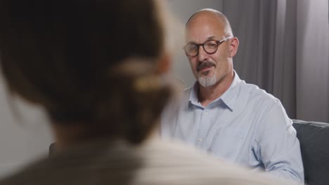 mature man sitting on sofa talking with female counsellor about general or mental health issue 13