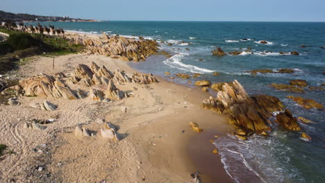 Tropical-sandy-beach-covered-in-rubbish-in-Vietnam,-aerial-ascend-view