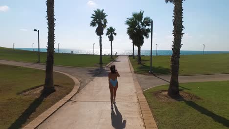 girl walkin through palm trees. drone slow-motion