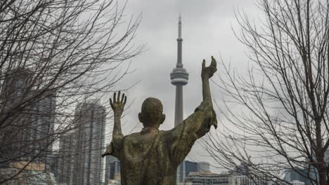 Timelapse-De-Nubes-Por-La-Torre-Cn-Detrás-De-La-Estatua-Del-Hombre-Jubiloso-En-Toronto