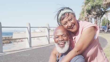 Portrait-of-happy-senior-african-american-couple-embracing-on-promenade-by-the-sea,-slow-motion