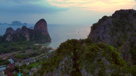 railay beach with traditional longtail boats dotting the andaman sea, surrounded by towering limestone cliffs at sunrise, krabi, thailand. nice aerial view flight overflight flyover reverse drone