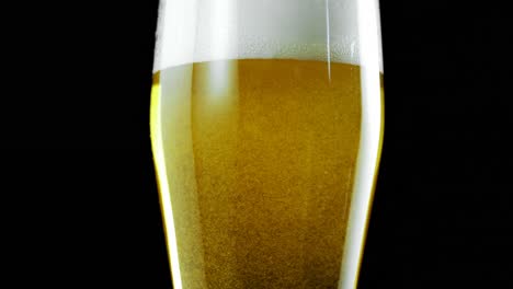 Glass-of-beer-against-black-background-4k