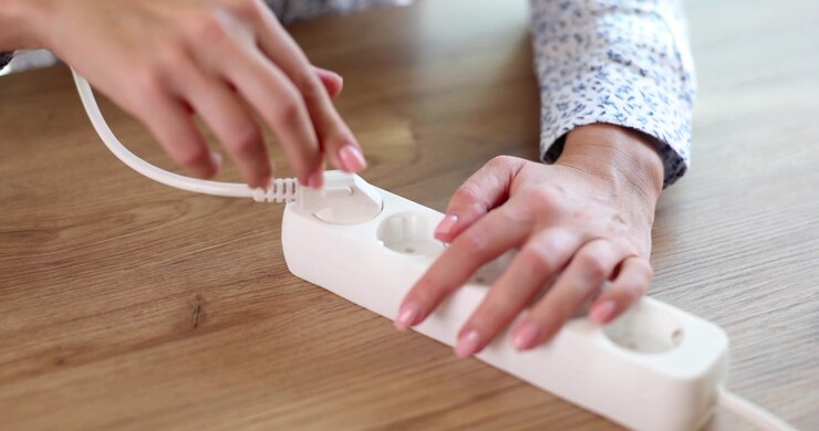 Woman office worker inserts plug into electrical extension cord