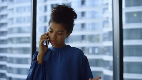 Displeased-businesswoman-having-conversation-on-smartphone-with-colleague