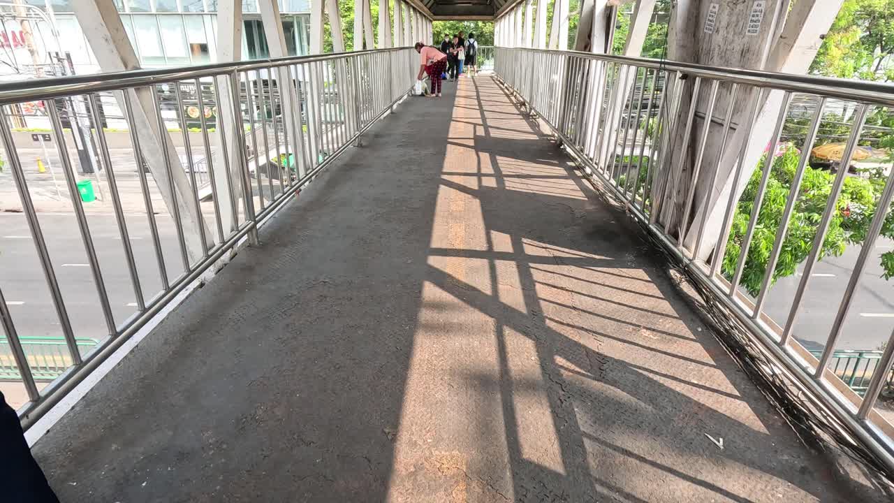 personas caminando por un puente peatonal con sombras