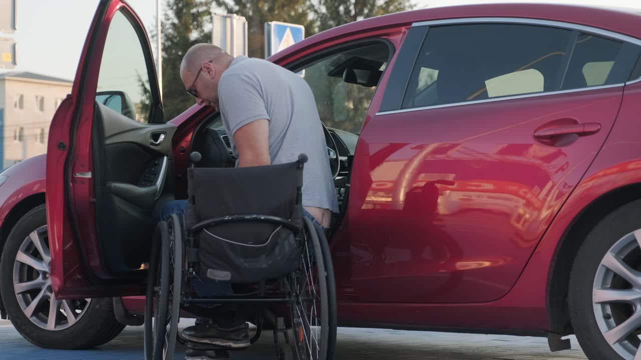 jovem condutor deficiente a entrar num carro vermelho de cadeira de rodas