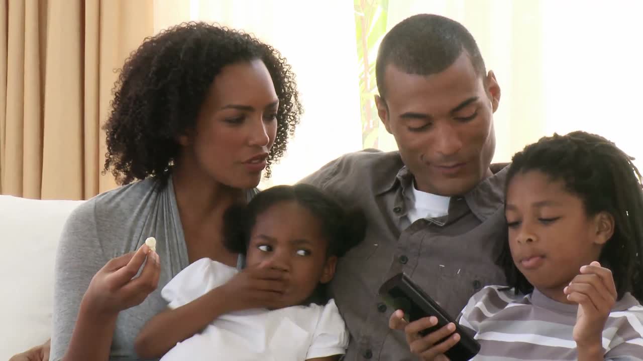 Primo piano di genitori e figli afroamericani che guardano la televisione