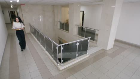 people walking in a modern office building hallway with glass railings