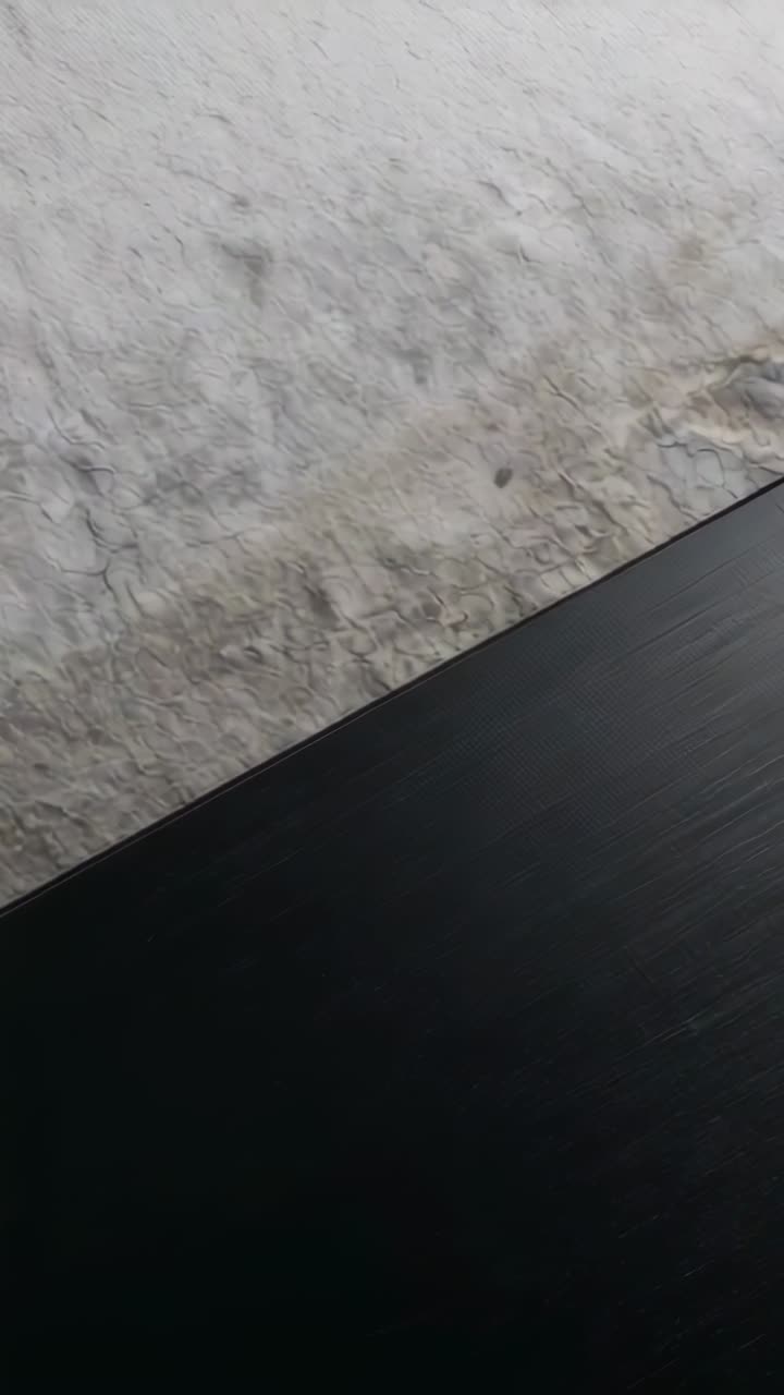 Vertical video: Panning camera showing rough plaster wall in room, with dark panel edge, copy space