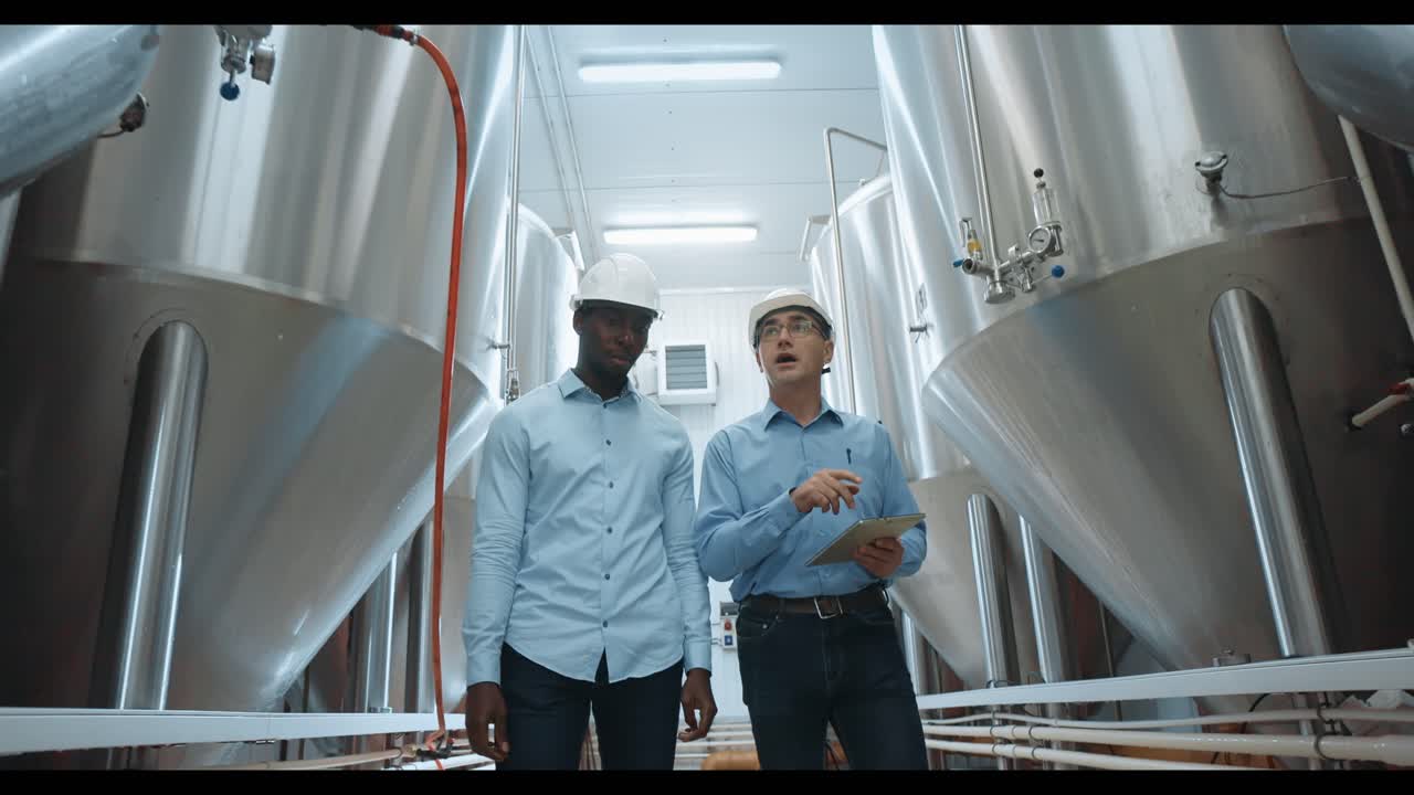 Two workers reviewing equipment in a brewery