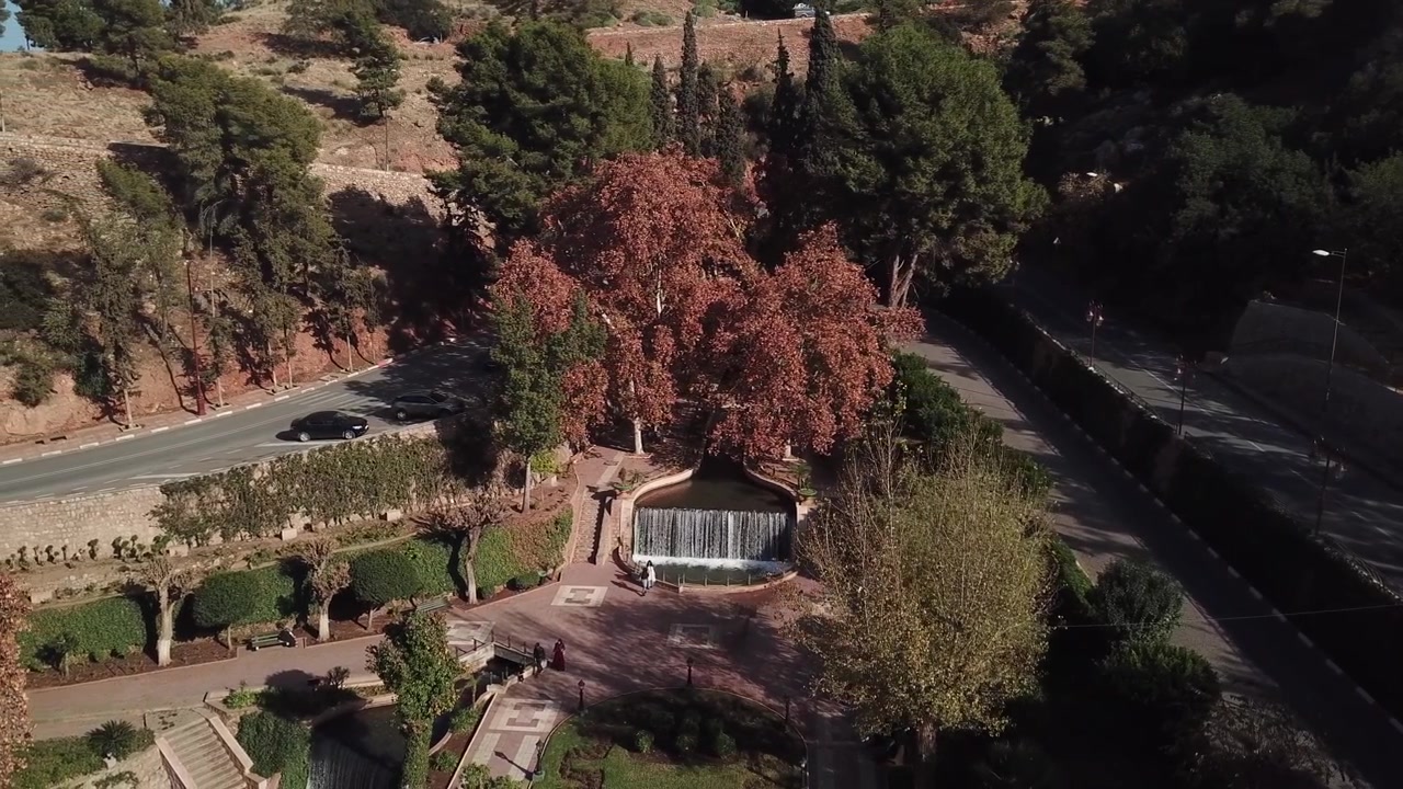 Vista aérea con dron de la cascada Ain Asserdoun en Beni Mellal, Marruecos, con agua de manantial en cascada rodeada de jardines paisajísticos y las estribaciones del Atlas
